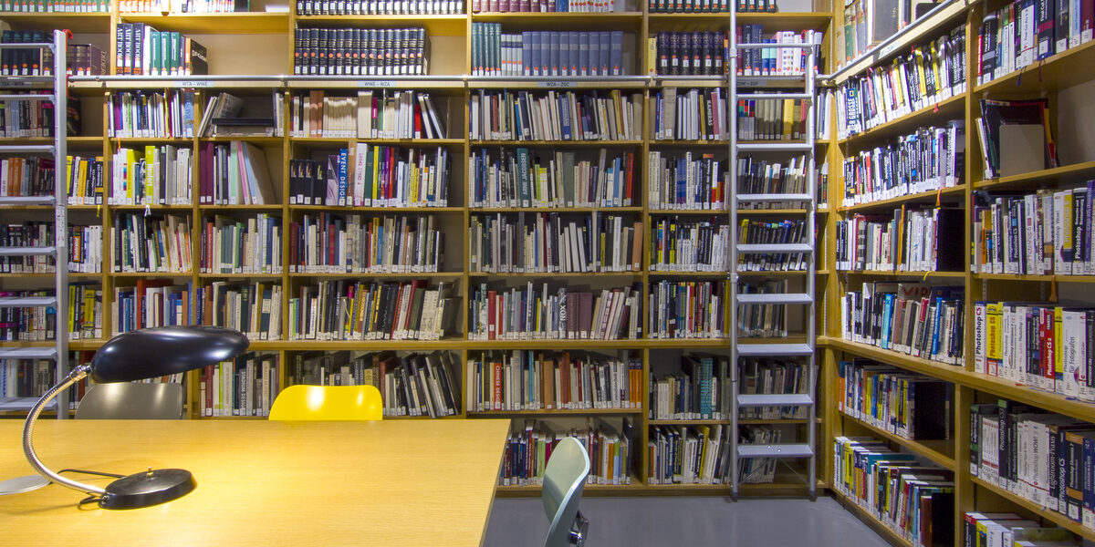 Photo of the library reading room with book shelves, desks, reading lamps and chairs__Photo of the library reading room with book shelves, desks, reading lamps and chairs