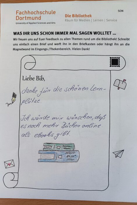 Foto von einem Brief an die Bibliothek mit einer Zeichnung von zwei gestapelten Büchern und dem Text: Liebe Bib, danke für die schönen Lernplätze. Ich würde mir wünschen, dass es noch mehr Bücher online als Ebooks gibt.__Photo of a letter to the library featuring a drawing of two books in a pile and the following text: Dear Library, thank you for the nice study desks. I wish more books were available online as e-books.