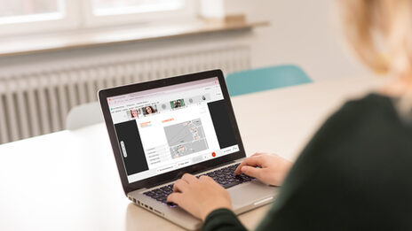 Foto einer Studentin, die an einem Laptop sitzt, auf dem eine Videokonferenz geöffnet ist. __<br>Female student looks at the screen of the laptop where a video conference is open.