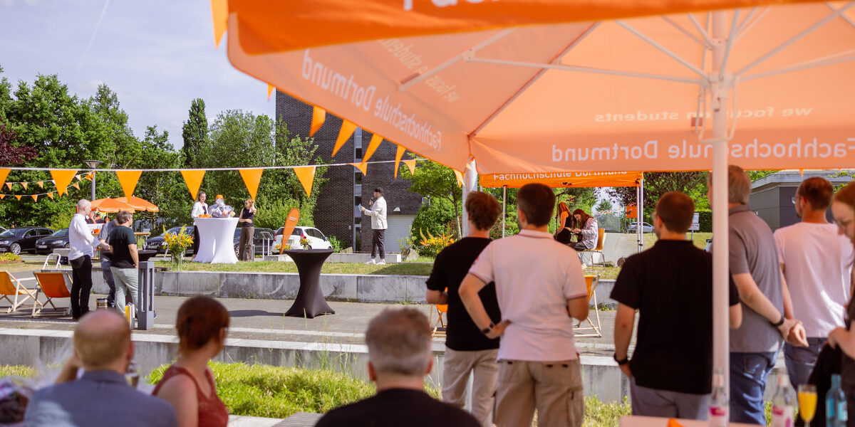 Impression of the Summer Festival 2023. People stand on the Emil-Figge-Straße campus and watch the stage program.