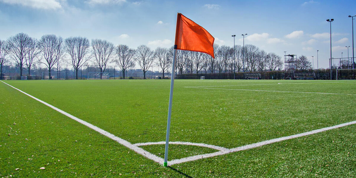 Auf einem Fußballfeld steht eine Eckfahne im Vordergrund.