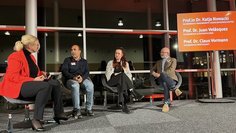 Mehrere Personen sitzen für eine Podiumsdiskussion zusammen.