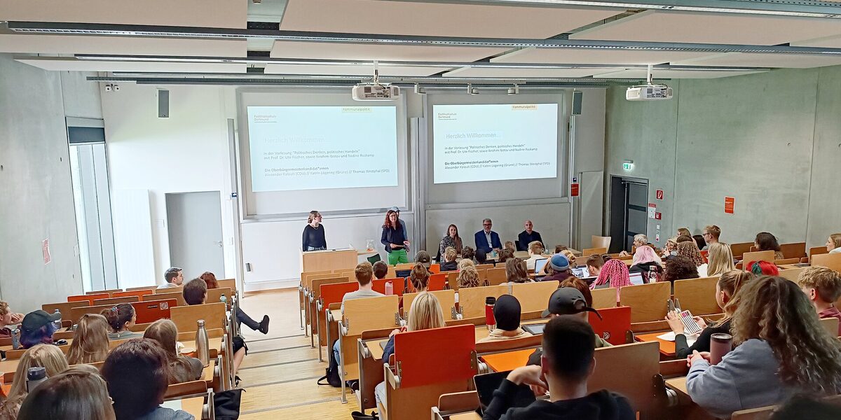 Vorlesung im Hörsaal U33, in der der Saal voll ist und im Vordergrund die Professorin Ute Fischer Gäste vorstellt