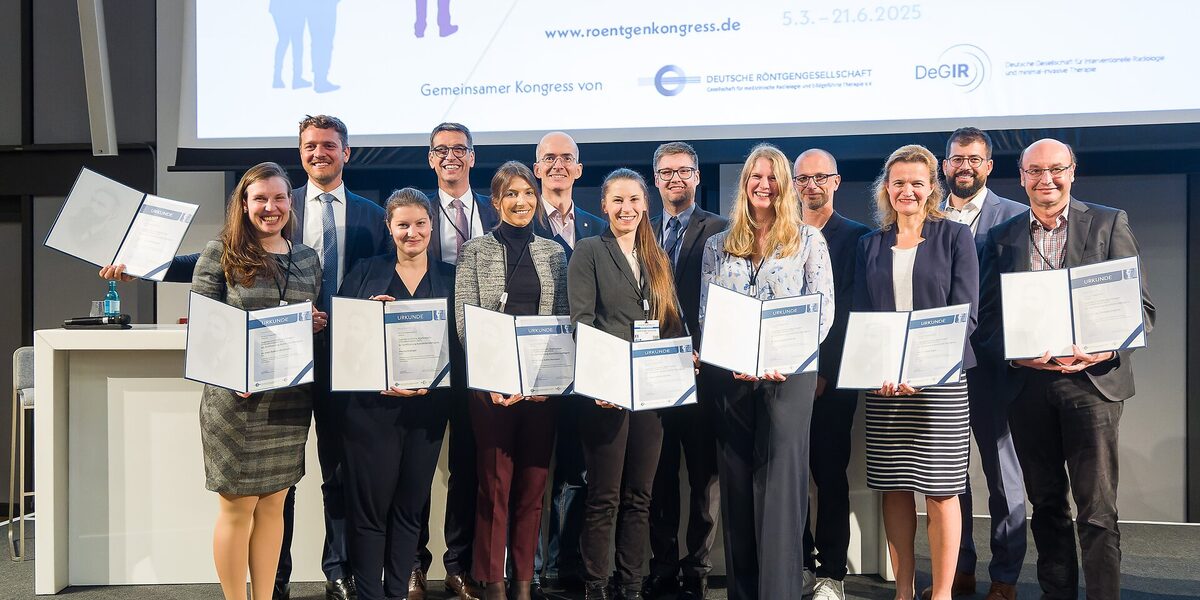 Gruppenbild mit mit mehreren Personen, die jeweils eine Urkunde vor sich halten.