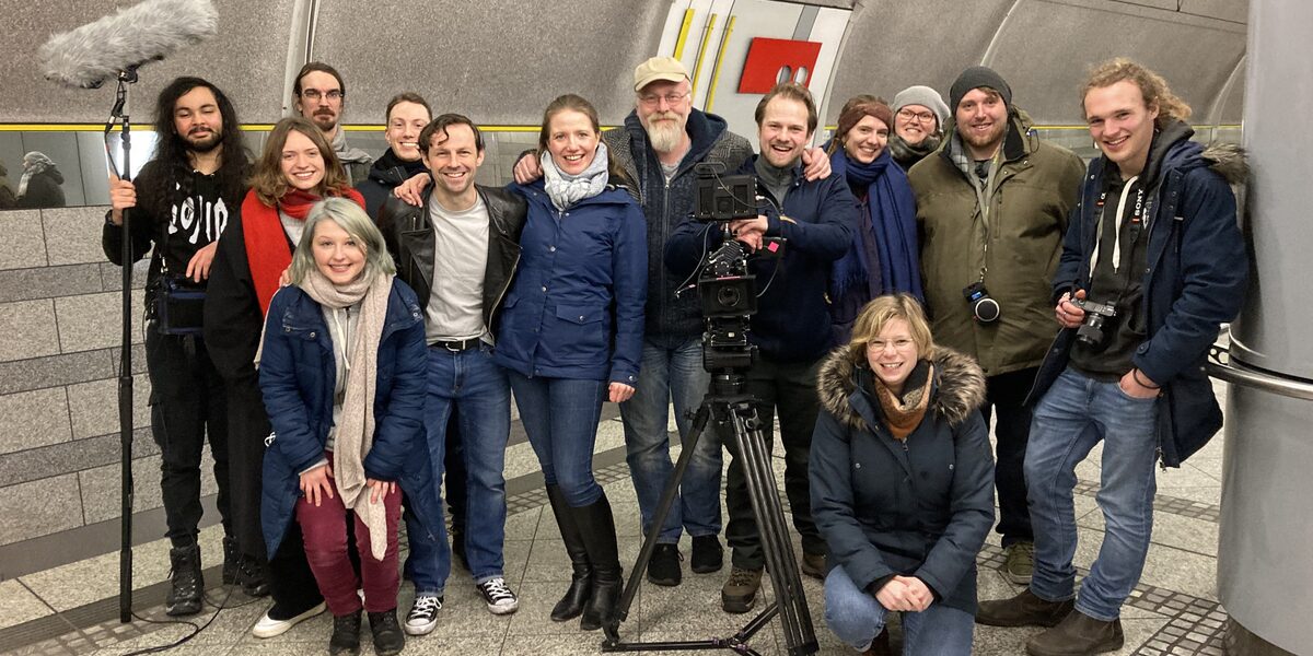 Group picture in a subway station with camera tripod and microphone angel