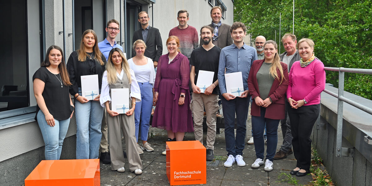Eine Gruppe von Menschen steht um orangefarbene Würfel. Einige von ihnen halten Urkunden.
