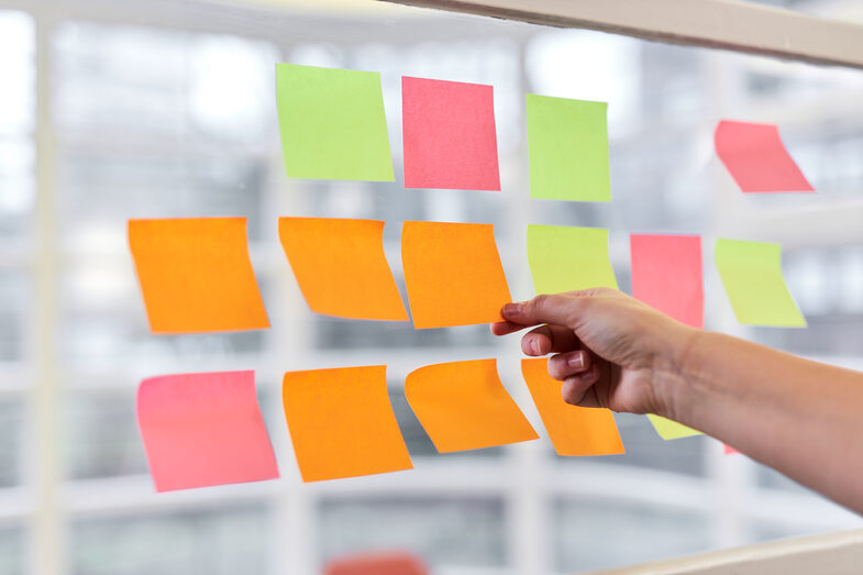Colorful Post-It's are sorted on a glass wall.