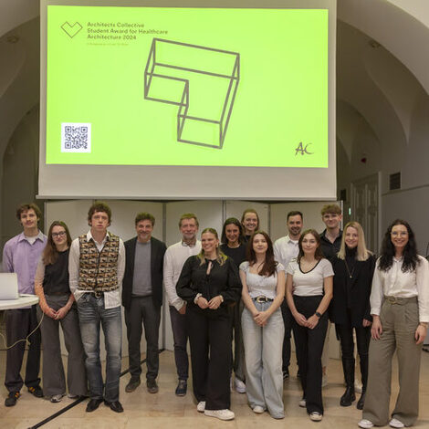 Gewinner des Architects Collective Student Award for Healthcare Architecture auf der Bühne vor einer Leinwand.