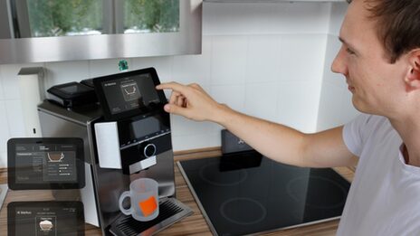 Smarte Kaffeemaschine als Haushaltsassistent, die ein junger Mann bedient.