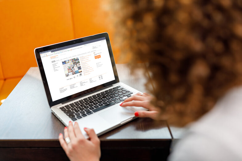 Photo over the shoulder of a female student on a laptop visiting the website of Fachhochschule Dortmund on her laptop __A female student is sitting and visiting the website of Fachhochschule Dortmund on her laptop.