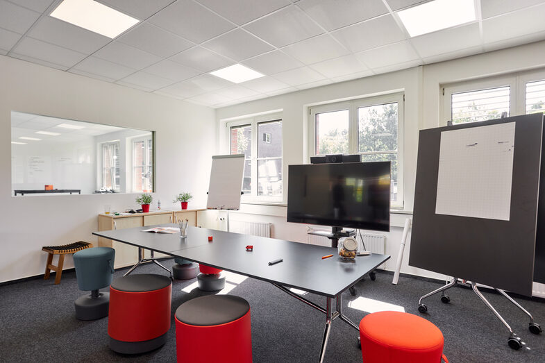 Room shot with a conference table, flipchart, digital board and note board.