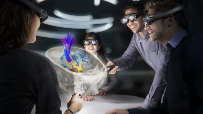 Four young people look at a cross-section of a human skull with various anatomical structures through virtual reality glasses.